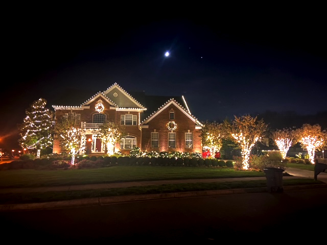 big nice house with outside lighting at night, trees with lights